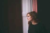 Nachdenkliche Frau lehnt sich zu Hause an Tür — Stockfoto