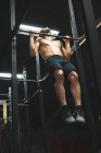 М'язистий чоловік тренується тягнути вгору на барі в спортзалі — стокове фото
