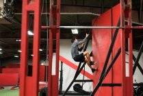 Musculoso hombre escalando una pared con cuerda en el gimnasio - foto de stock