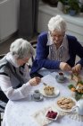 Amis seniors prenant le petit déjeuner ensemble à la maison — Photo de stock
