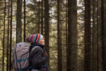 Nachdenkliche Seniorin steht mit Rucksack im Wald — Stockfoto