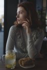 Nachdenkliche Frau mit Zitronentee und Wrap Food sitzt im Café — Stockfoto