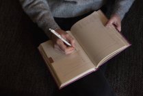 Женщина пишет записку о дневнике в гостиной дома — стоковое фото