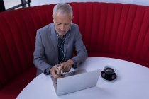 Бізнесмен, використовуючи мобільний телефон під час роботи на ноутбуці у лобі готелю — стокове фото