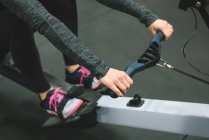 Close up of muscular woman exercising on rowing machine at gym — Stock Photo
