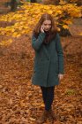 Woman talking on mobile phone in the park during autumn — Stock Photo
