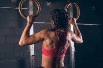 Підходить жінка тягне гімнастичні кільця в спортзалі — стокове фото