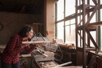 Femme bowling scie poussière de planche dans l'atelier charpentier — Photo de stock