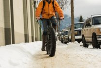 Человек ездит на велосипеде по тротуару зимой — стоковое фото