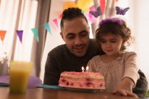 Padre e hija celebrando cumpleaños en la sala de estar en casa - foto de stock
