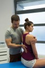 Fisioterapeuta retribuindo massagem à mulher na clínica — Fotografia de Stock