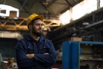 Nachdenklicher Techniker steht mit verschränkten Armen in der Metallindustrie — Stockfoto