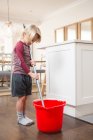 Хлопчик тримає підлоговий мопед з відром вдома — стокове фото