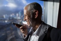 Close-up of businessman talking on mobile phone in hotel room — Stock Photo