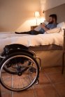 Disabled man using mobile phone in bedroom at home — Stock Photo