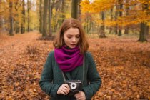 Femme tenant caméra vintage dans le parc pendant l'automne — Photo de stock