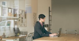 Ejecutivo masculino trabajando en el ordenador portátil en la oficina - foto de stock