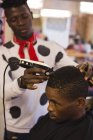 Barbeiro aparar o cabelo do cliente na barbearia — Fotografia de Stock