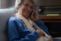 Senior woman talking on mobile phone at home — Stock Photo