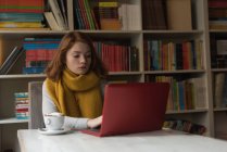 Mulher usando laptop na sala da biblioteca — Fotografia de Stock