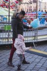 Padre e hija caminando con algodón de azúcar en el parque de atracciones - foto de stock