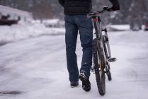 Rear view of man walking with bicycle on snowy street — Stock Photo