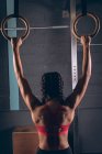 Вид спереду підходить жінці, займається гімнастичними кільцями в тренажерному залі — стокове фото