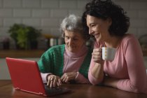 Mother and daughter using laptop in kitchen at home — Stock Photo
