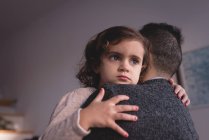 Батько обіймає доньку у вітальні вдома — стокове фото