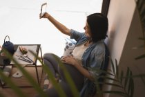 Pregnant woman talking selfie with mobile phone at cafe — Stock Photo
