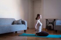 Молода жінка практикує йогу у вітальні вдома — стокове фото
