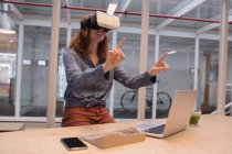 Женщина-руководитель, использующая гарнитуру виртуальной реальности в офисе — стоковое фото