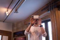 Мужчина, использующий гарнитуру виртуальной реальности в офисе — стоковое фото