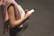 Schwangere benutzt Handy an einem sonnigen Tag — Stockfoto