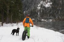 Uomo con bicicletta guardando il cane su un paesaggio innevato durante l'inverno — Foto stock
