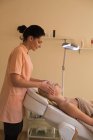 Косметичка даючи обличчя масаж жіночий клієнта в салон — стокове фото