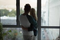 Пара обіймає один одного біля вікна вдома — стокове фото