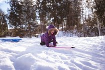 Cute girl playing with sled in snow during winter — Stock Photo