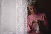 Active senior woman knitting wool at home — Stock Photo