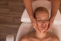 Estetista dando massaggio viso al cliente femminile in salotto — Foto stock