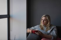 Nachdenkliche Frau beim Kaffee im heimischen Wohnzimmer — Stockfoto