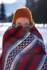 Femme souriante enveloppée dans la couverture dans la neige — Photo de stock