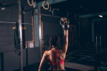 Visão traseira da mulher em forma exercitando com kettlebell no ginásio — Fotografia de Stock