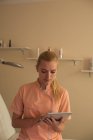 Молодая женщина косметолог с помощью цифрового планшета в гостиной — стоковое фото