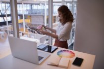 Женщина графический дизайнер глядя на цветную книгу образцов в офисе — стоковое фото