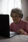 Активная пожилая женщина с ноутбуком дома — стоковое фото