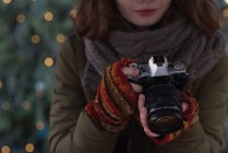 Средняя часть женщины в зимней одежде держит винтажную камеру — стоковое фото