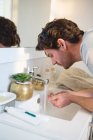 Uomo che si lava il viso con acqua in bagno a casa — Foto stock