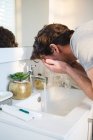 Homme se laver le visage avec de l'eau dans la salle de bain à la maison — Photo de stock