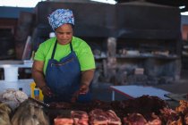 Fleischereifachverkäuferin schneidet Fleisch an Theke in Metzgerei — Stockfoto